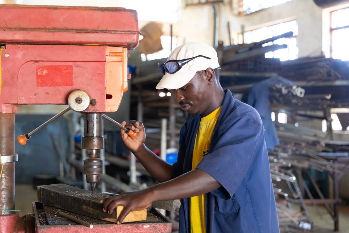 A trainee operating a pillar drill in the engineering workshop